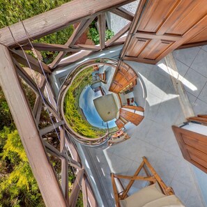 A circular outdoor seating area with a central table and chairs, surrounded by wooden beams and glass walls, offering a view of the surrounding greenery. - Valentina apartments (Hersonissos)