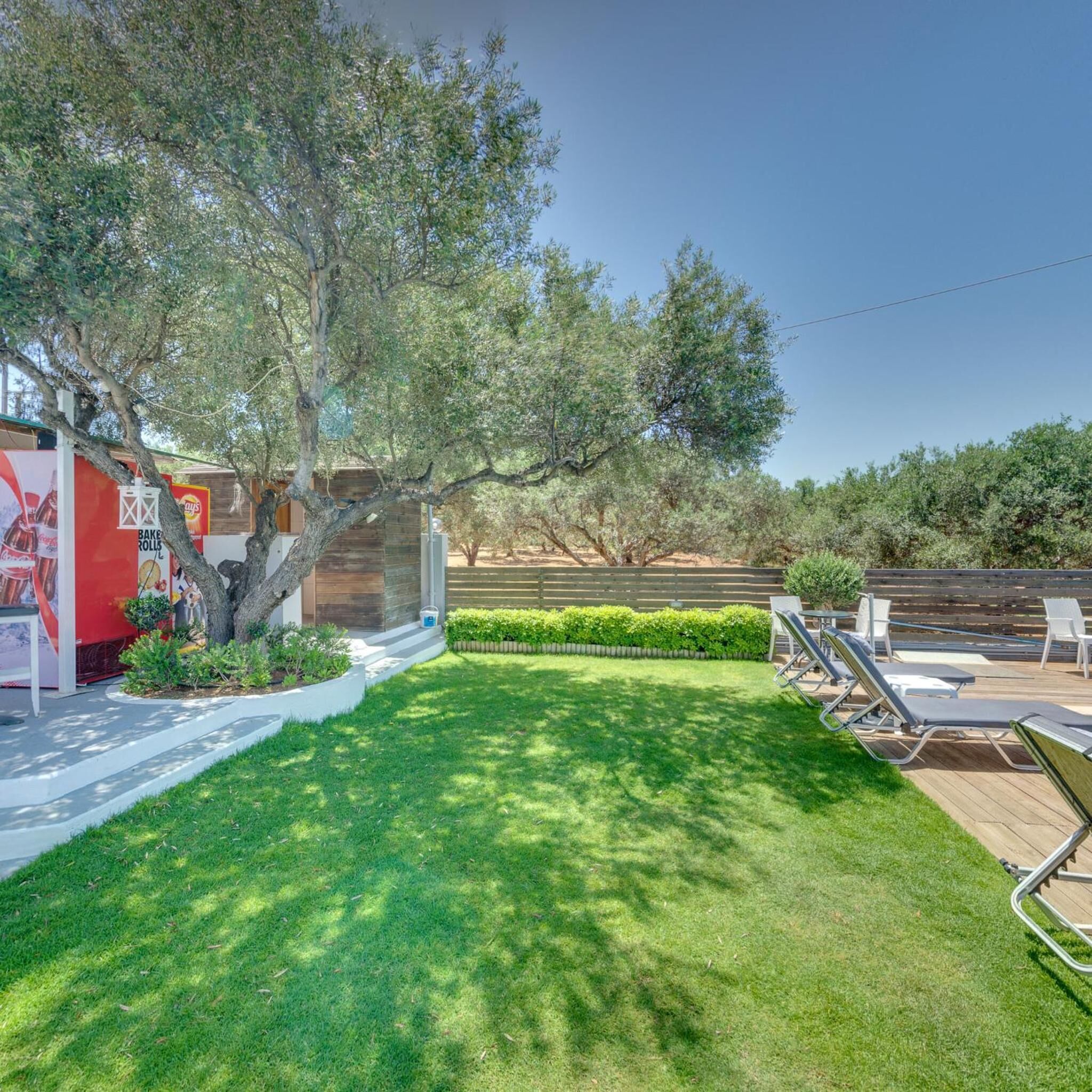 A backyard with a wooden deck, a barbecue grill, and a pool area with lounge chairs.