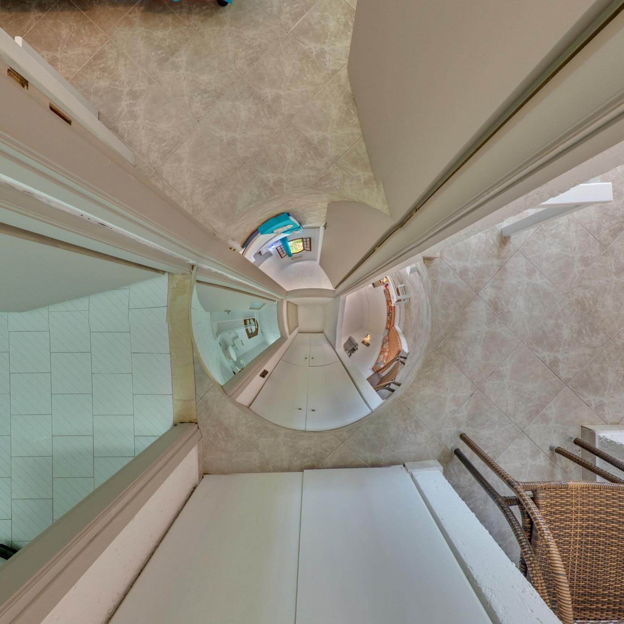 A high-ceilinged, circular room with a central seating area and a view of a bathroom with a bathtub and a shower.