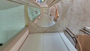 A high-ceilinged, circular room with a central seating area and a view of a bathroom with a bathtub and a shower. - Valentina apartments (Hersonissos)
