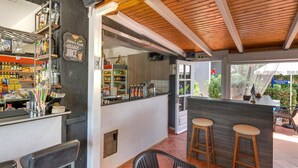 A restaurant with a bar area, outdoor seating, and a view of the swimming pool. - Valentina apartments (Hersonissos)