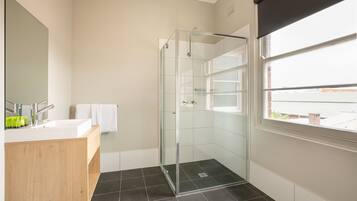Un bagno moderno con doccia vetro, mobile bagno in legno e uno specchio grande.