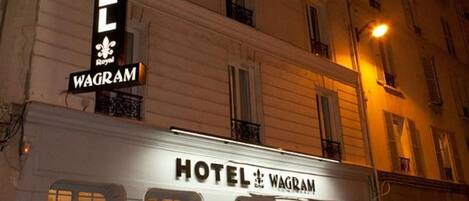 A hotel named "HOTEL WAGRAM" with a prominent sign, a white facade, and a car parked in front.