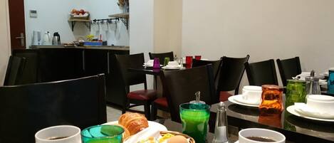 A dining area with multiple tables, chairs, and a variety of breakfast items including croissants, eggs, and beverages.