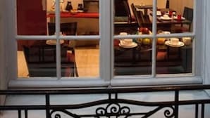 Una finestra con vista su una sala da pranzo, comprensiva di tavoli e sedie.