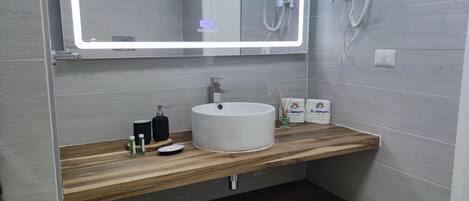 A modern bathroom with a wooden vanity, a white sink, and a mirror with a lighted frame.