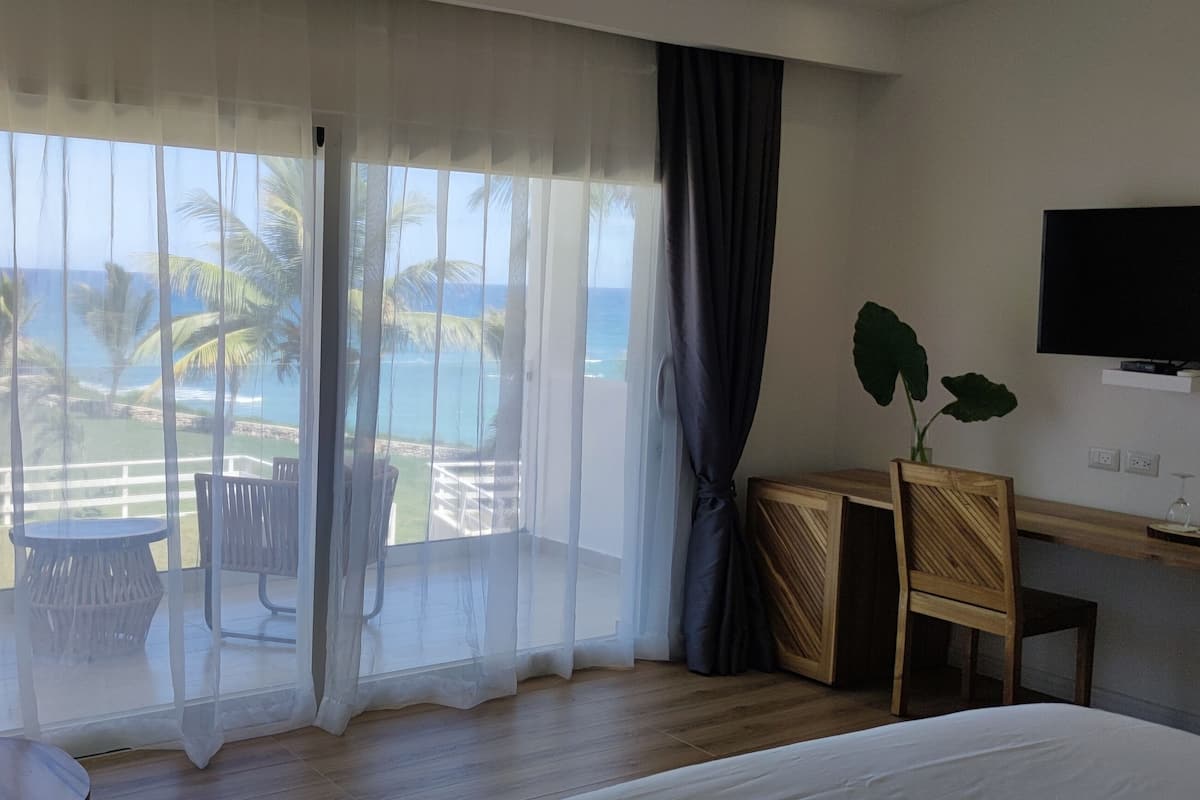 Une chambre d’hôtel avec une grande fenêtre, un lit, une télévision, un bureau et une chaise.