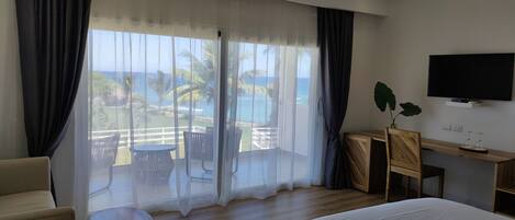 A hotel room with a large window, a bed, a TV, a desk, and a chair.