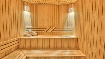 A sauna with wooden walls and benches, a bench with a towel, and two wall-mounted lights.