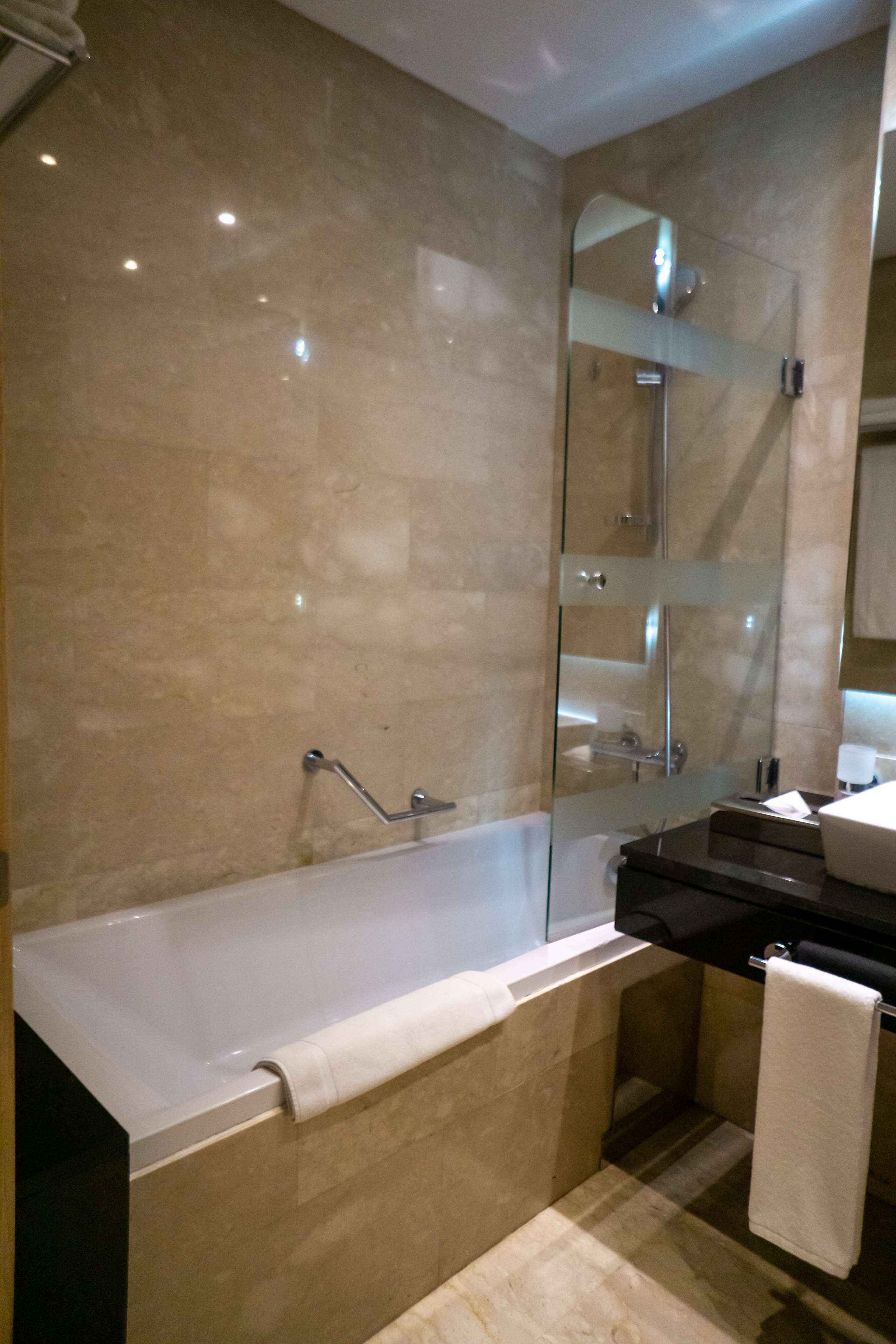A modern bathroom with a glass-enclosed shower, a bathtub, and a vanity with a mirror.