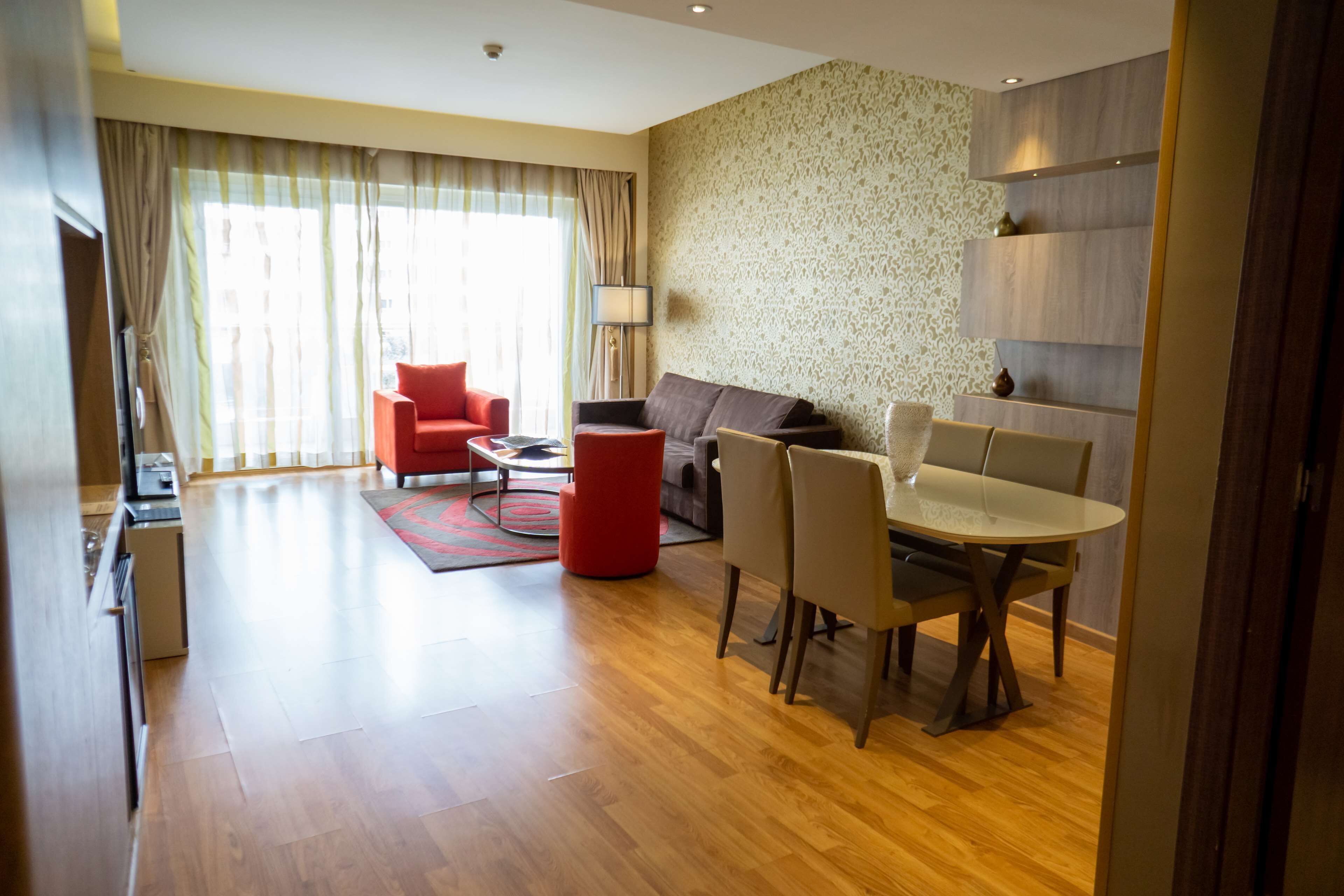 Ein modernes Wohnzimmer mit einer Couch, einem roten Sessel, einem Esstisch und Stühlen.