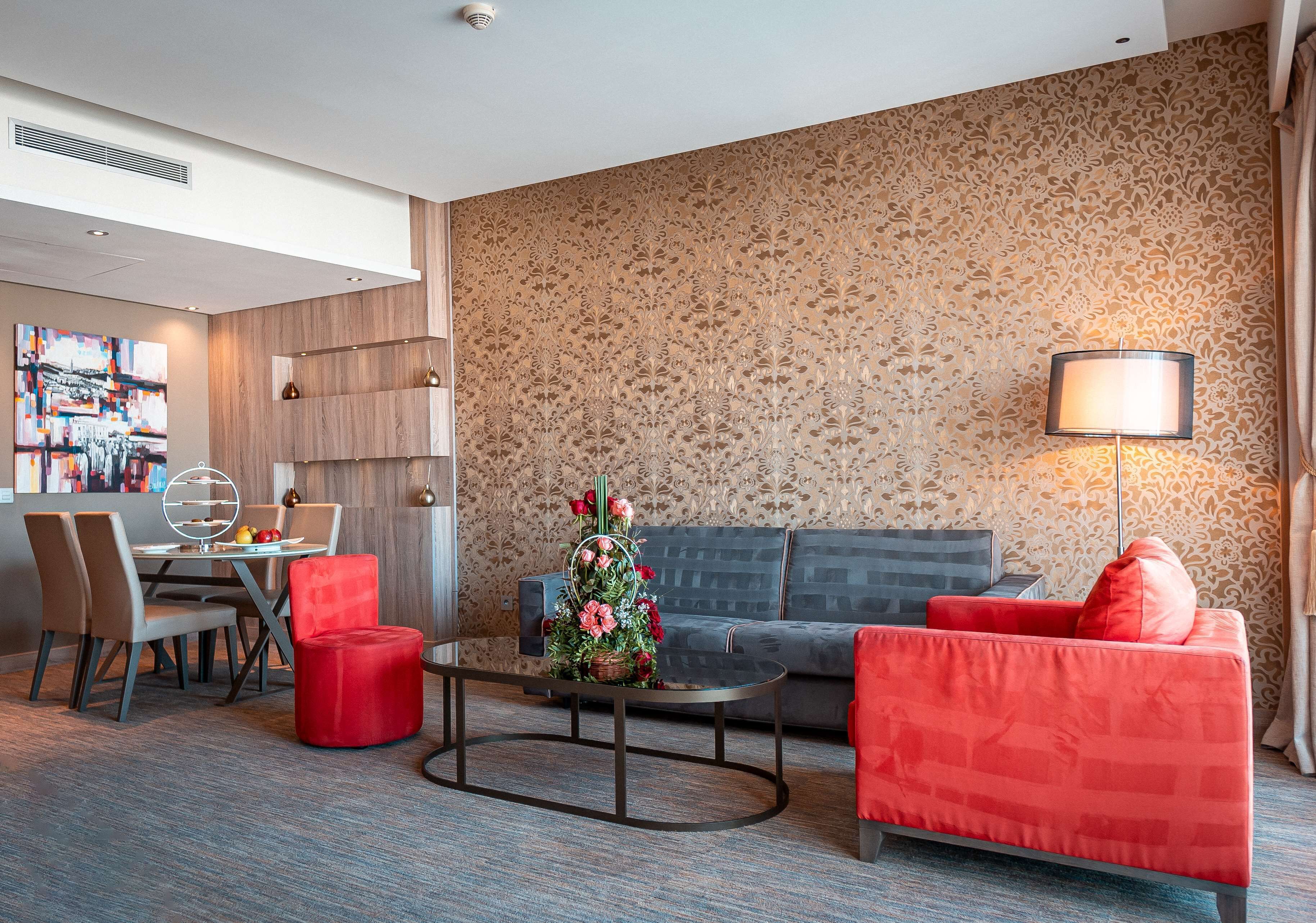 Una habitación de hotel moderna con zona de comedor, sofá y mesa de centro.