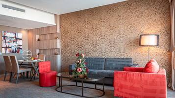 Una habitación de hotel moderna con zona de comedor, sofá y mesa de centro.