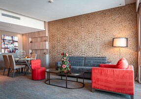 Una habitación de hotel moderna con zona de comedor, sofá y mesa de centro.