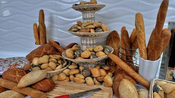 A variety of breads and loaves displayed on a table with a cutting board and utensils.