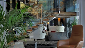 A modern living room with a leather armchair, a sofa, and a glass staircase. - Royal Tulip City Center Tanger (Tangier)