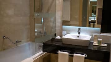 Une salle de bain moderne avec une douche à parois de verre, un grand lavabo et deux serviettes posées sur le comptoir.