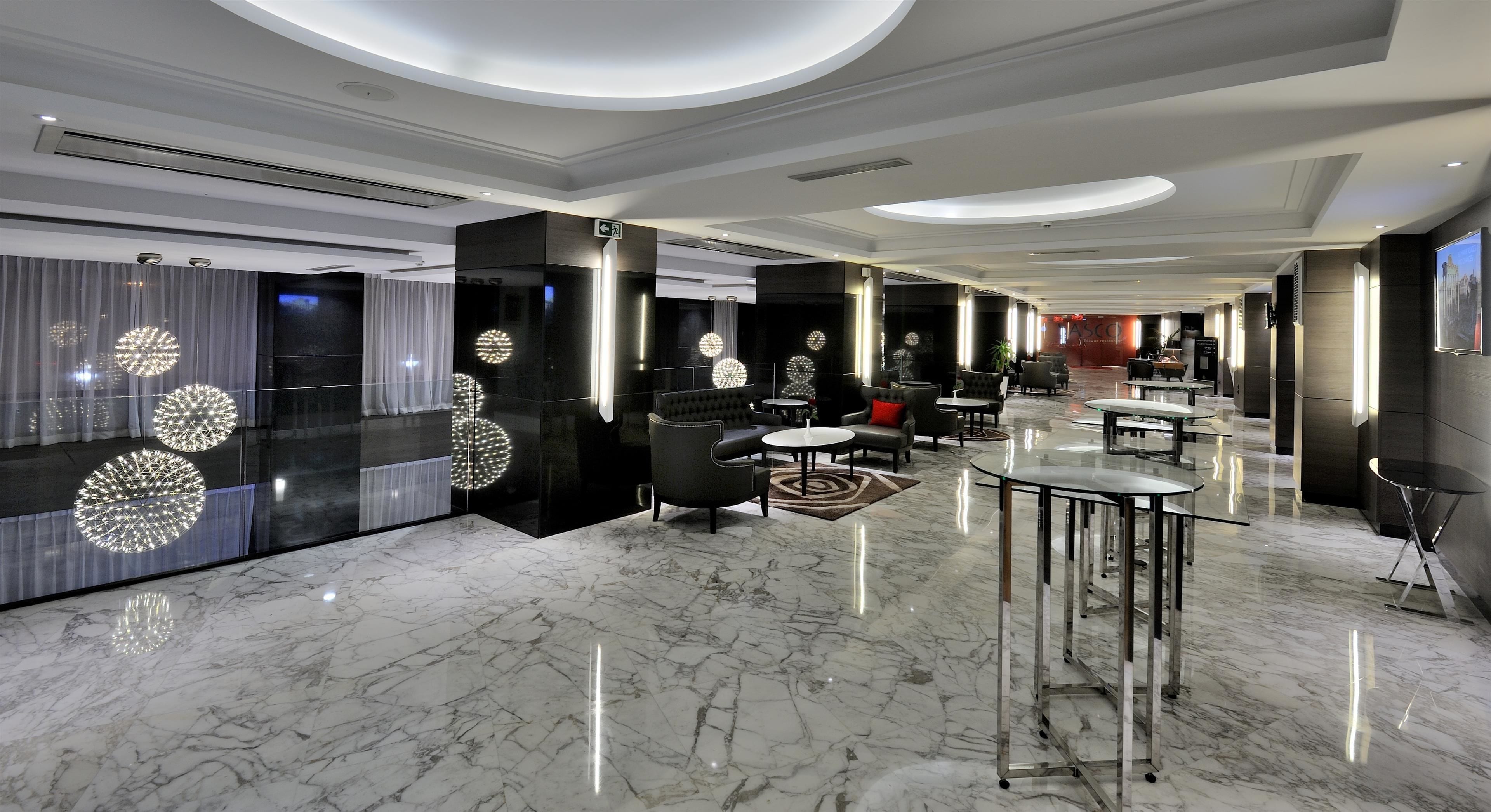 Een moderne hotellobby met marmeren vloeren, eigentijds meubilair en decoratieve verlichtingsarmaturen.