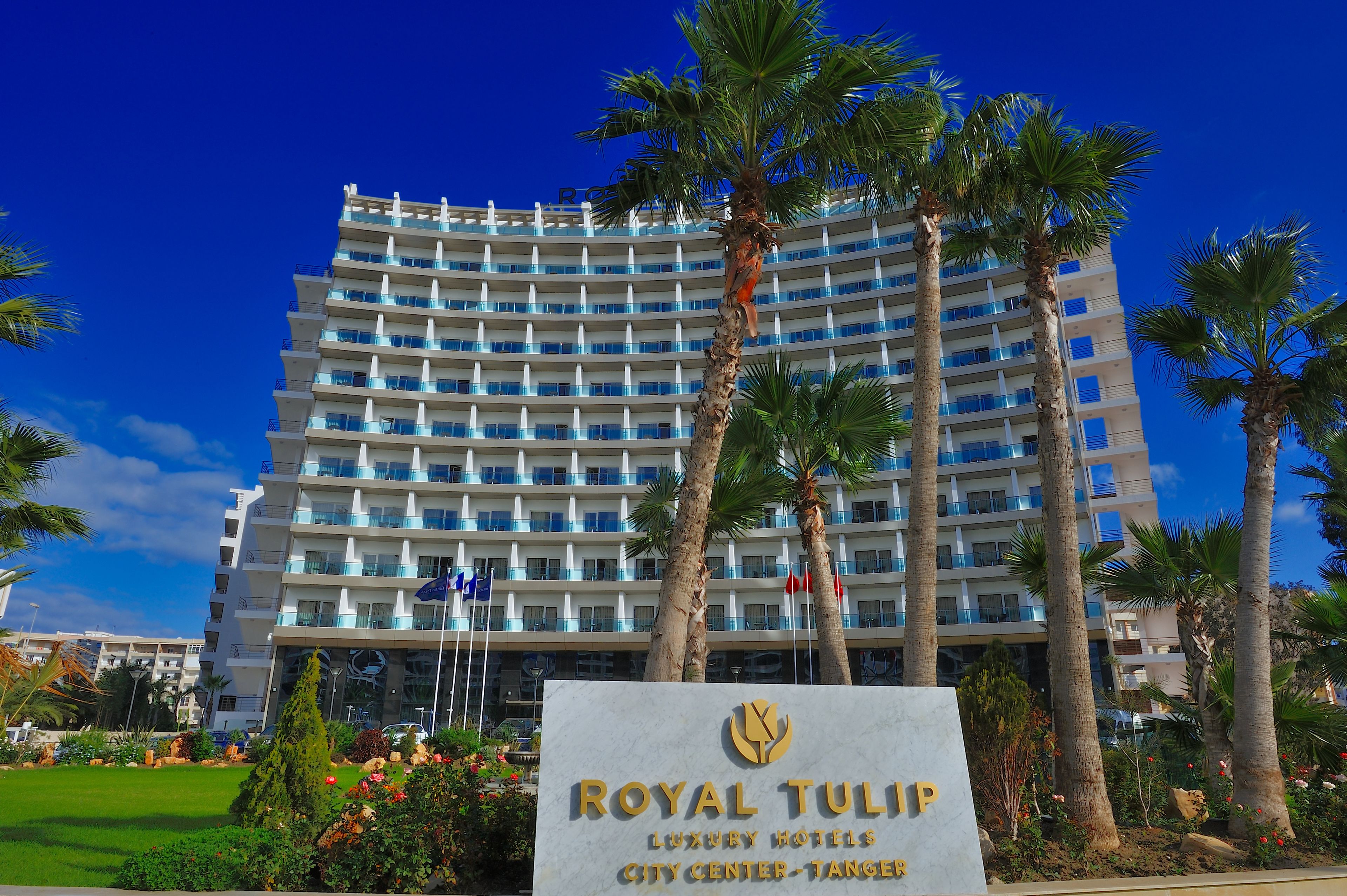 Un hotel de varios pisos con un letrero que dice "ROYAL TULIP LUXURY HOTELS CITY CENTER - TANGERE".