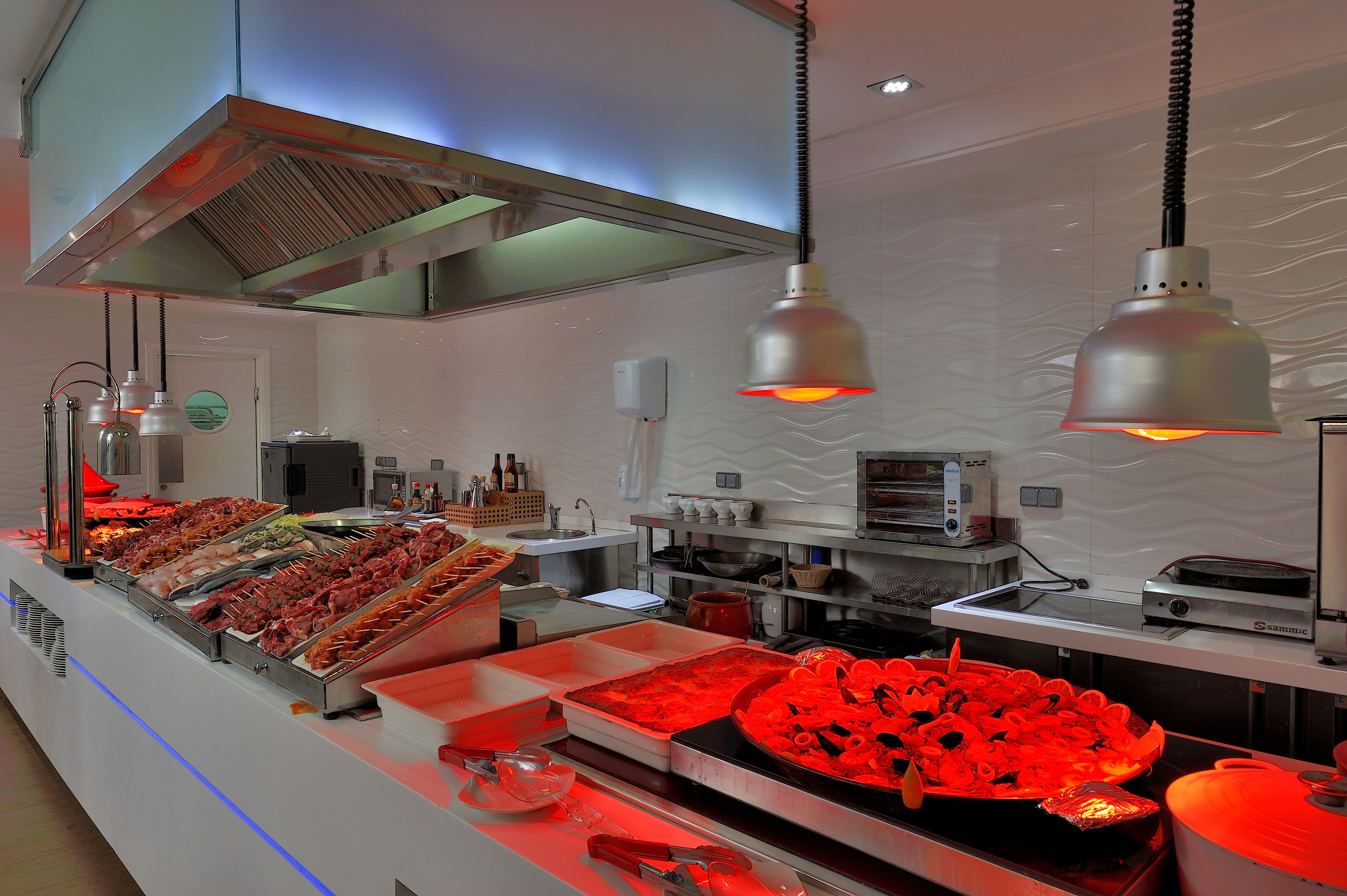 A buffet with various food items and a kitchen area with appliances.