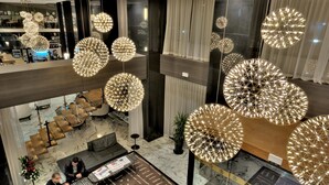 A hotel lobby with multiple seating areas, large chandeliers, and a visible reception desk. - Royal Tulip City Center Tanger (Tangier)