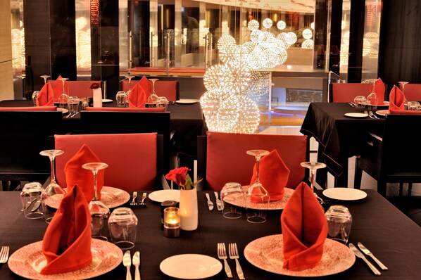 A restaurant with tables set for dining, featuring red napkins and clear glassware.