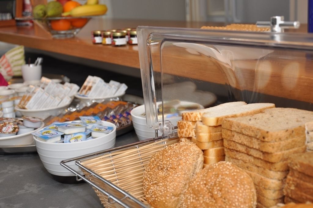 A buffet with various food items including bread, pastries, and condiments.