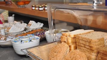 Een buffet met diverse soorten eten, zoals brood, gebak en toevoegingen.