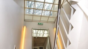 A modern interior with a glass ceiling, a staircase, and a green exit sign.