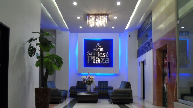 A hotel lobby with a modern design, featuring a reception desk, seating area, and a chandelier. - Hotel San Jose Plaza (Bucaramanga)