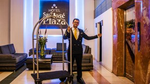 A hotel lobby with a sign reading "HOTEL San José Plaza," a seating area with sofas, and a luggage cart. - Hotel San Jose Plaza (Bucaramanga)
