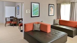 Ein modernes Wohnzimmer mit zwei Sofas, einem Esstisch mit Stühlen und gerahmten Kunstwerken an den Wänden.