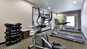 Ein Fitnessraum in einem Hotel mit Laufbändern, einem Crosstrainer und einer Hantelbank.