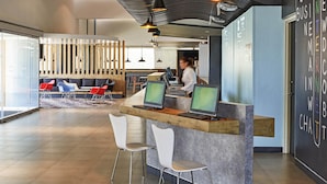 A modern reception area with a counter, two computer monitors, and a seating area with chairs and a sofa.