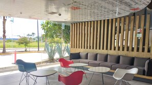 A modern indoor seating area with a wooden slat wall, a sofa, and various chairs. - Ibis Culiacan (Culiacán)