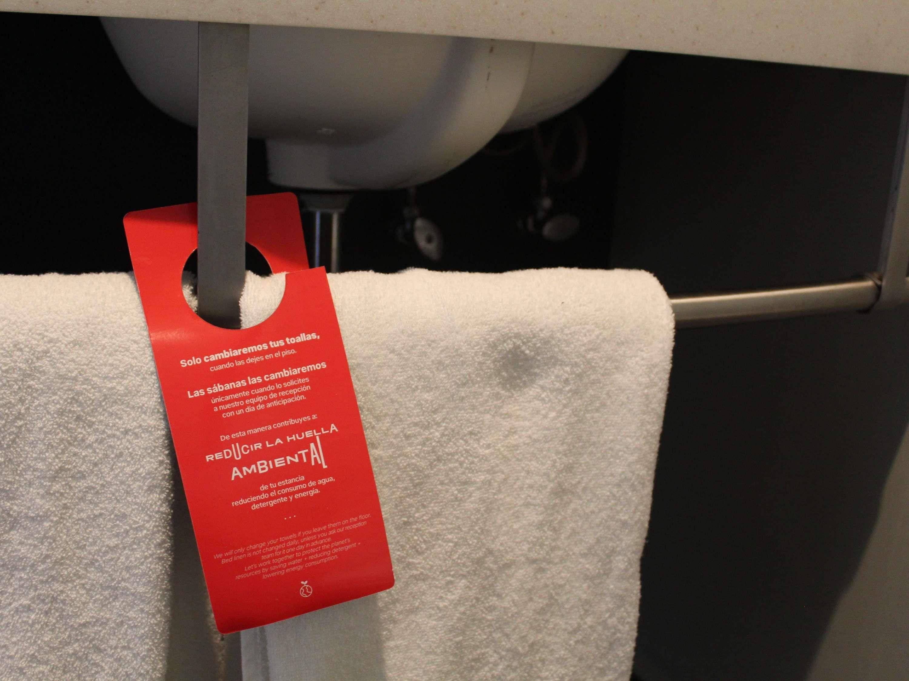 Une serviette blanche est suspendue sous un évier, et une étiquette rouge y est attachée.
