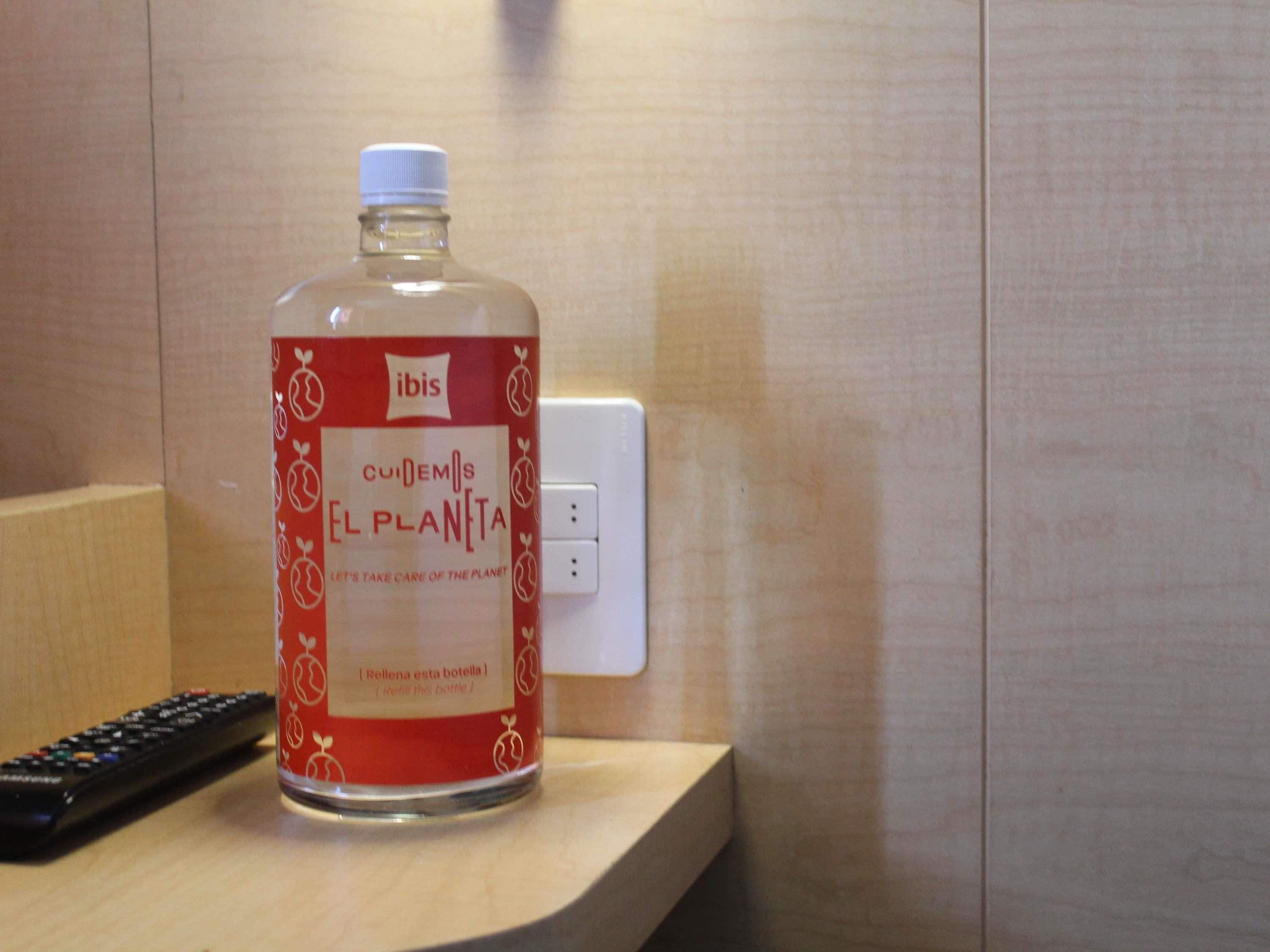 A bottle of 'Cuidemos el Planeta' water on a wooden surface next to a wall socket.