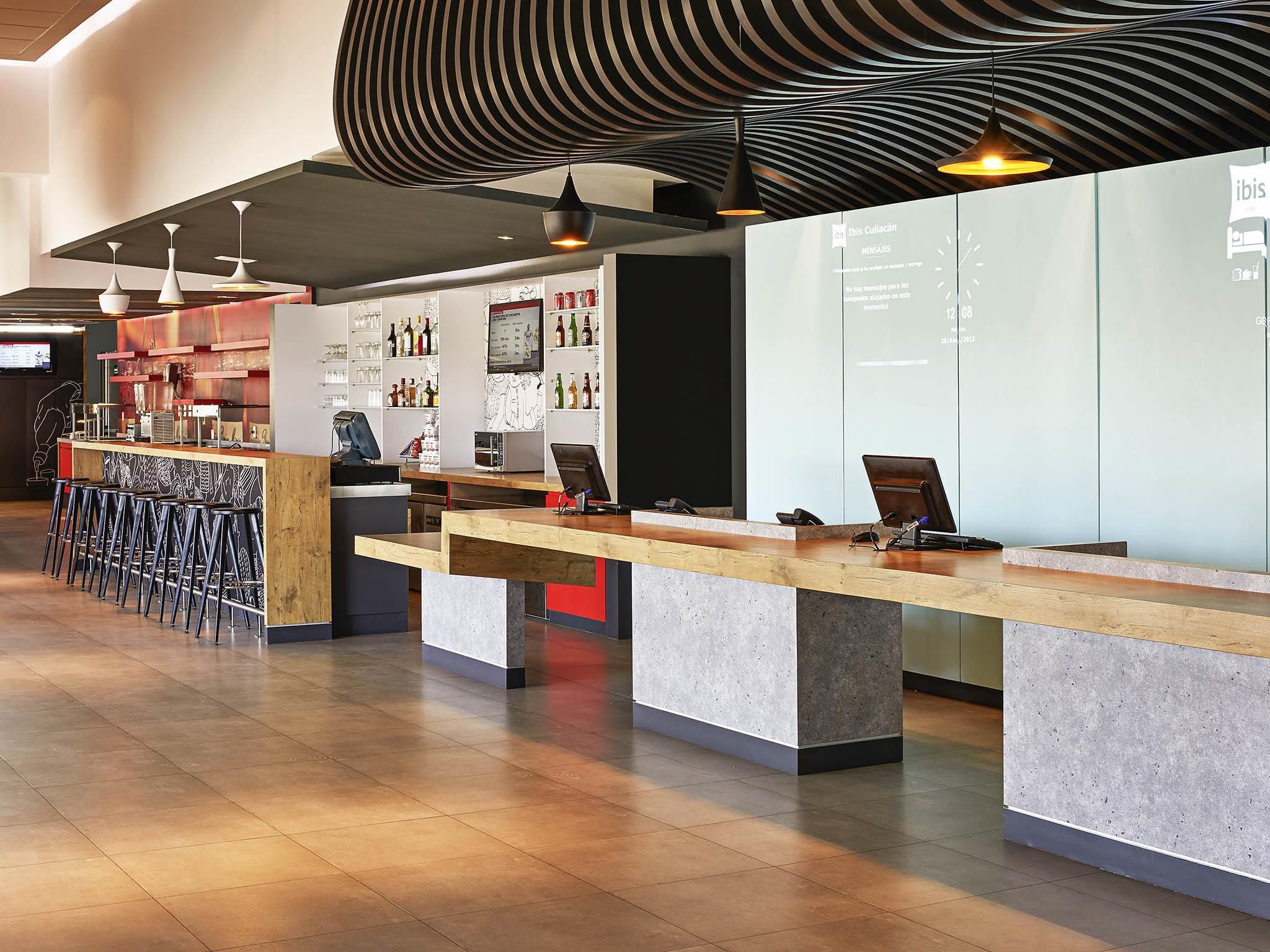 A modern bar area with a counter, stools, and a display of bottles.