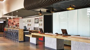 Zona de bar moderna con mostrador, taburetes y una exhibición de botellas.