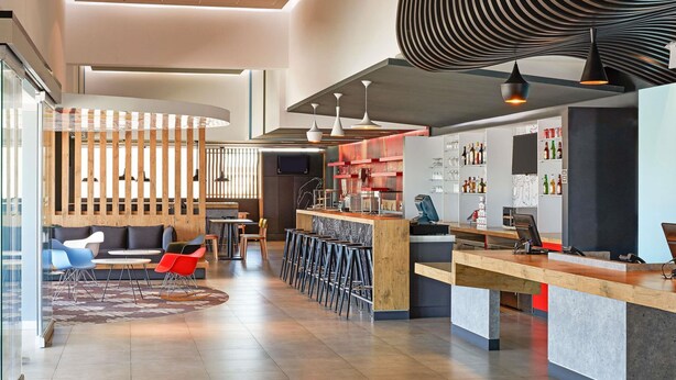 A modern interior with a bar area, seating, and a TV screen. - Ibis Culiacan (Culiacán)