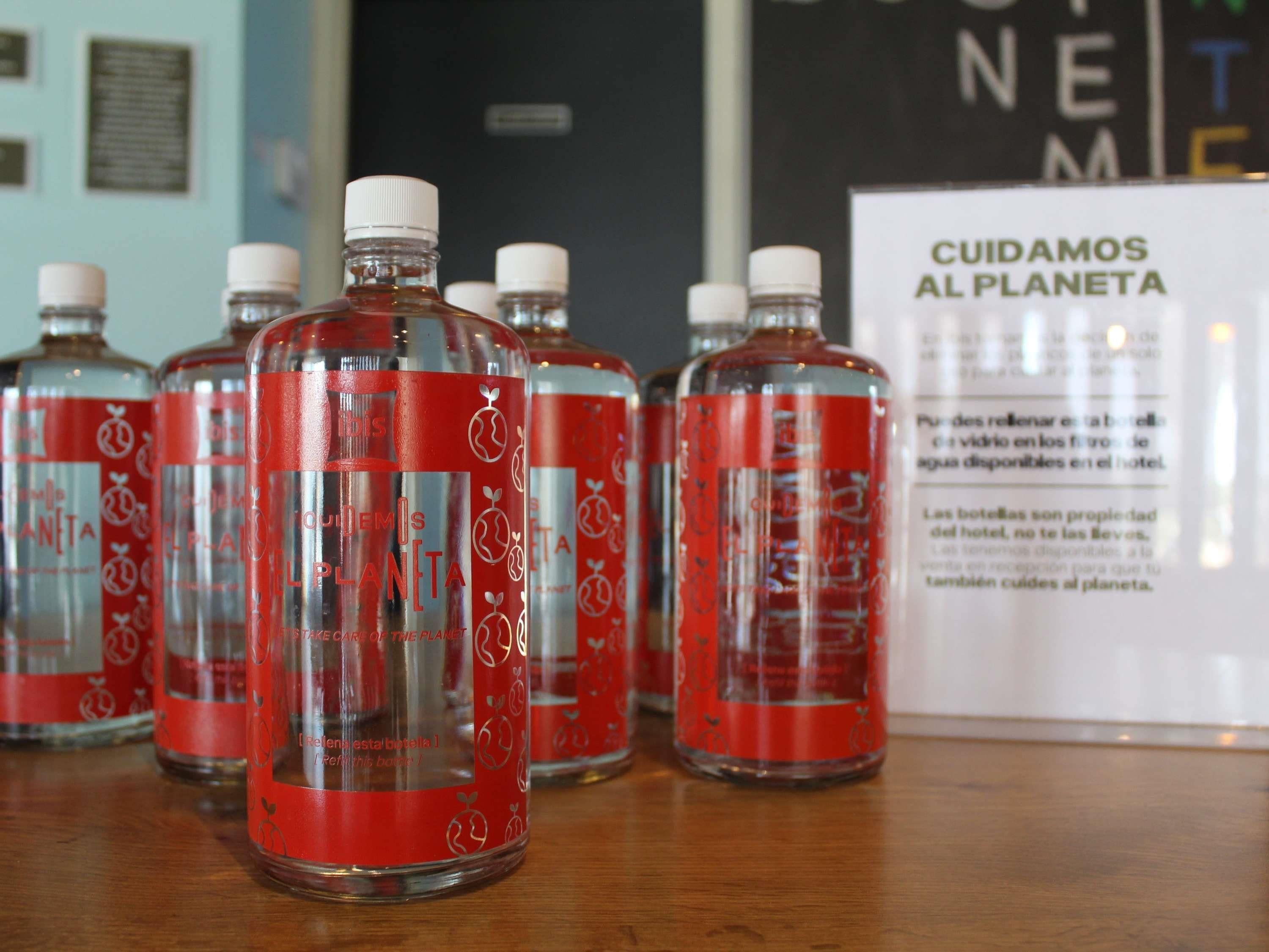 Several bottles with red labels and white caps, arranged on a wooden surface.