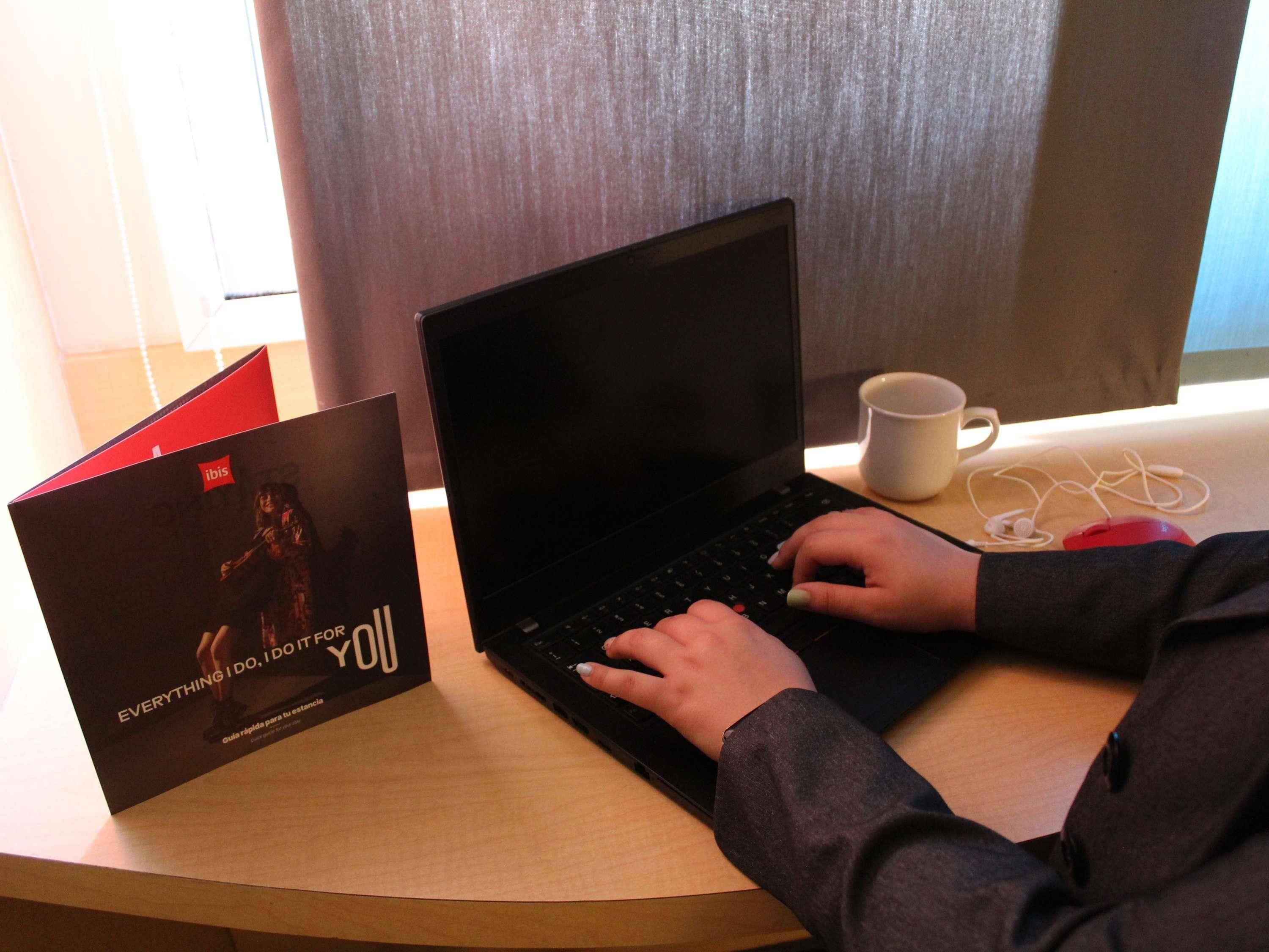 Una computadora portátil sobre un escritorio con un libro y una taza.