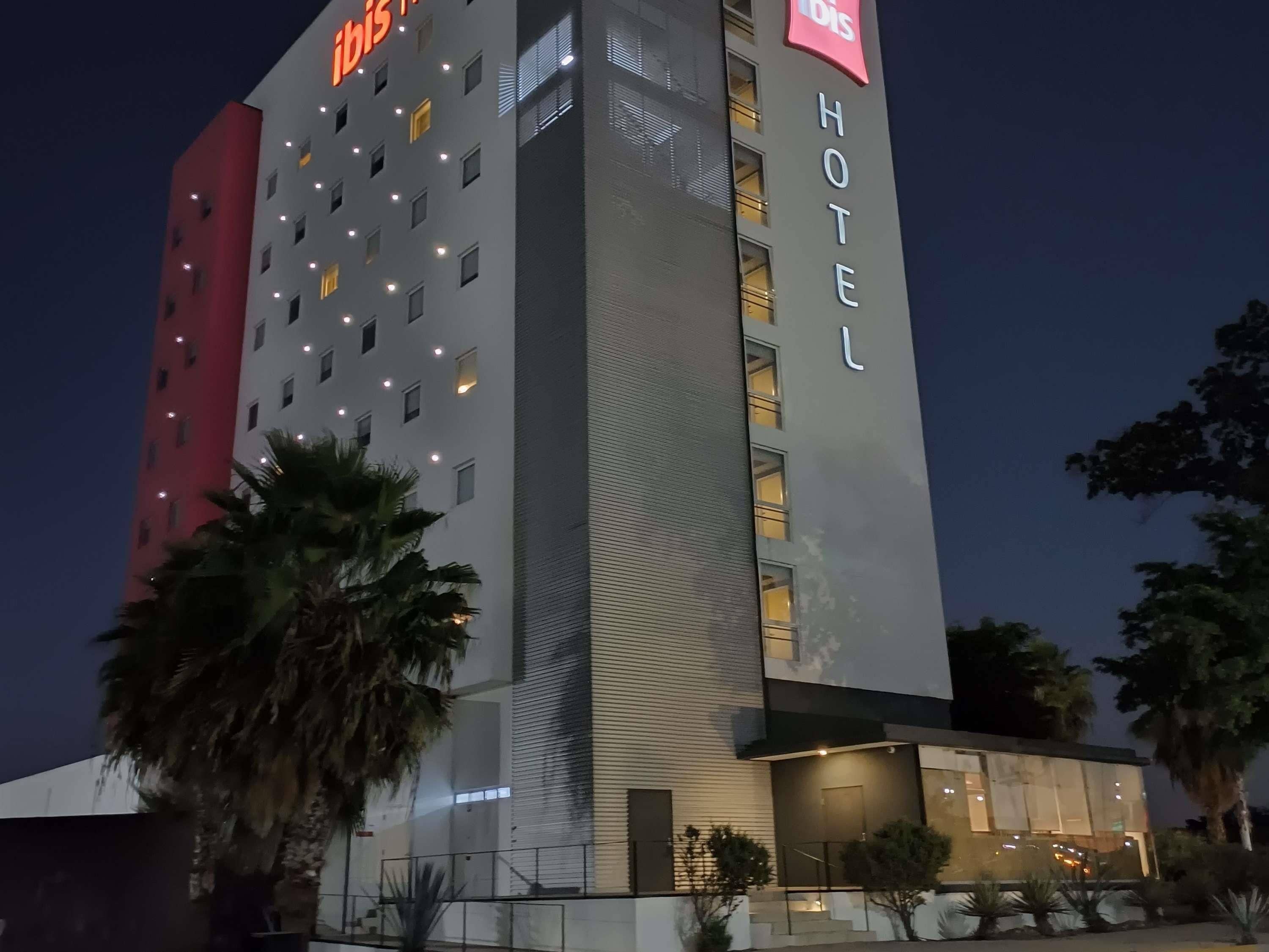 A multi-story hotel building with illuminated signage, a modern facade, and a well-lit entrance.