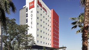 Un hotel moderno con una fachada llamativa de rojo y blanco, varios pisos y un área de entrada cubierta.