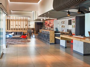 Un interior moderno con una zona de bar, asientos y una pantalla de televisión.