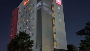 A multi-story hotel building with illuminated signage, a modern facade, and a well-lit entrance. - Ibis Culiacan (Culiacán)