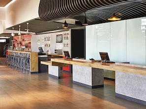 A modern bar area with a counter, stools, and a display of bottles. - Ibis Culiacan (Culiacán)