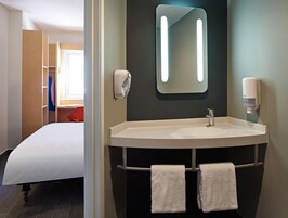 Habitación de hotel con una cama grande, un lavamanos redondo, un espejo y un perchero para toallas.
