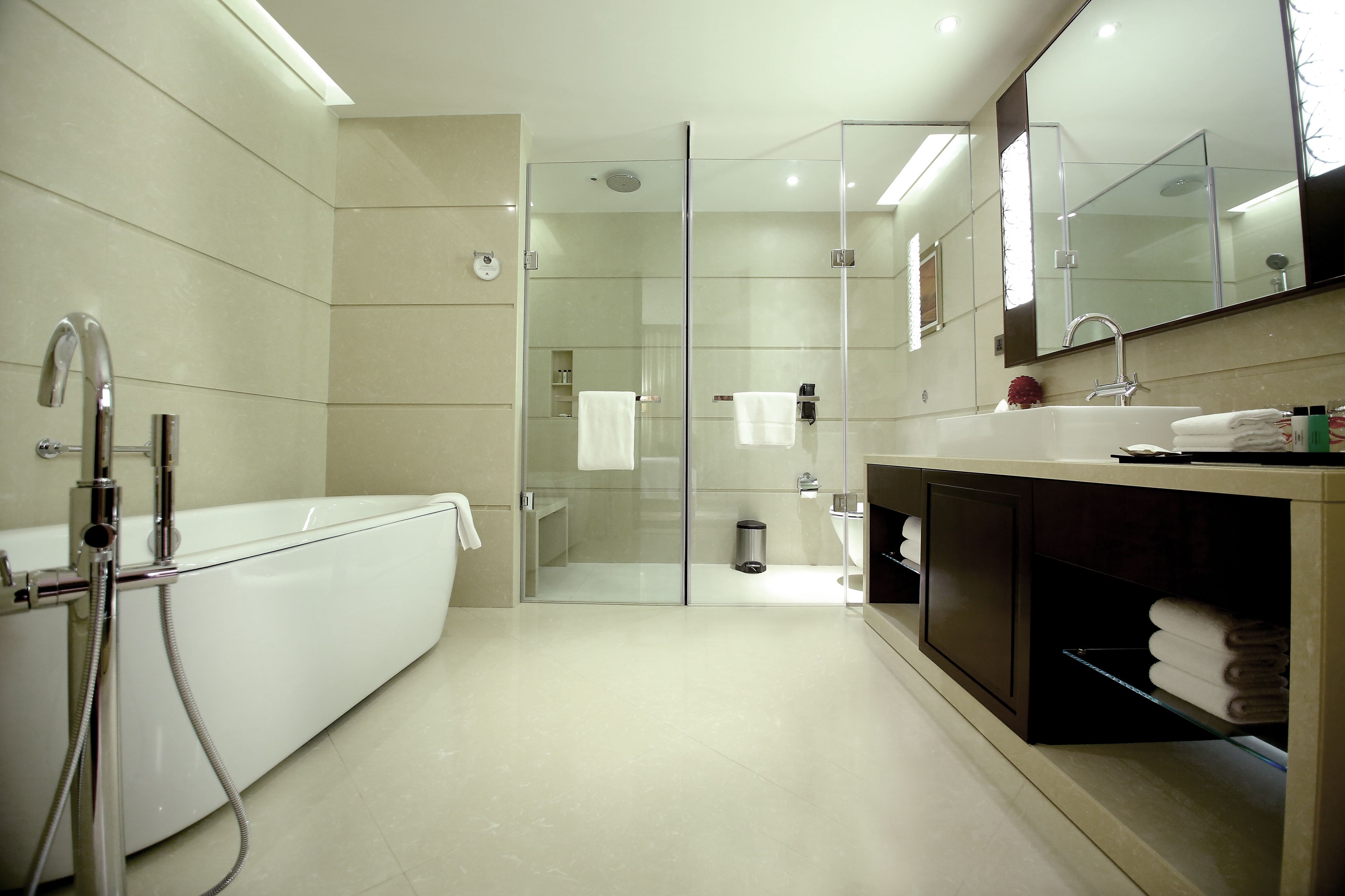 A modern bathroom with a glass-enclosed shower, a white bathtub, and a vanity with a mirror.