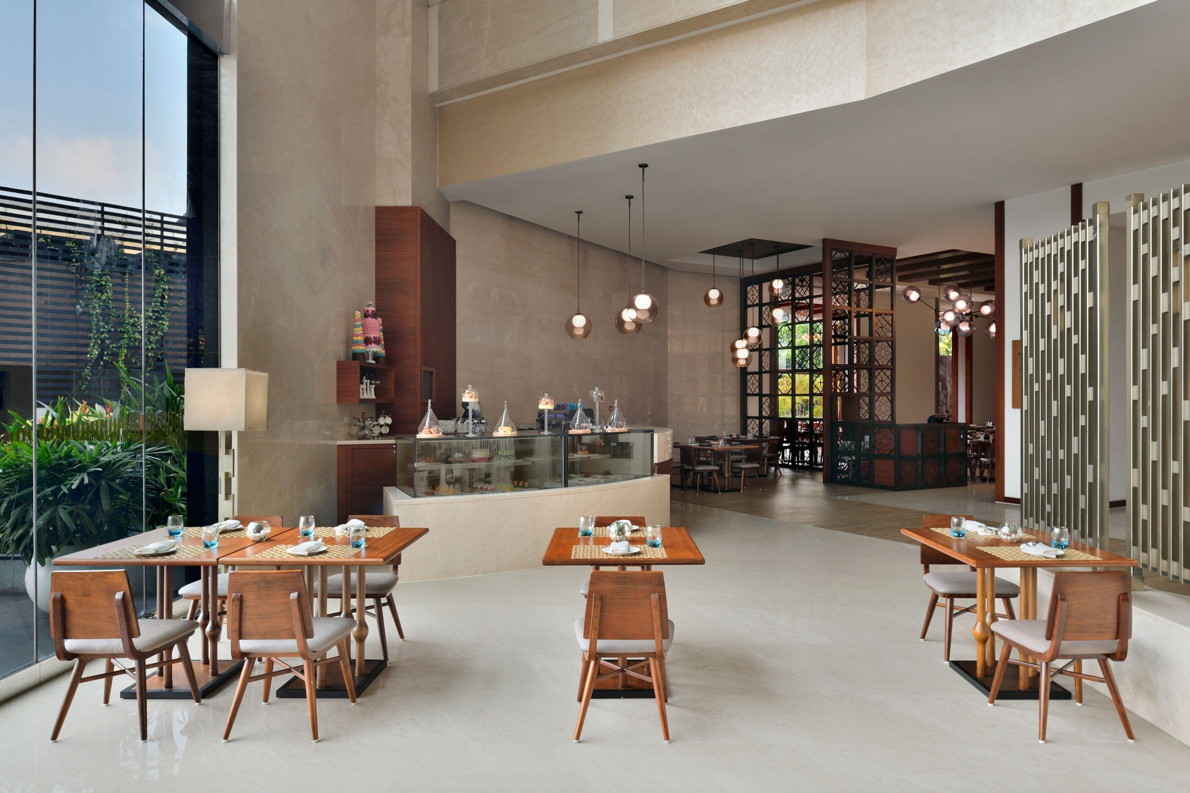 A spacious indoor dining area with multiple tables and chairs, a central counter with a display, and a decorative partition with hanging lights.